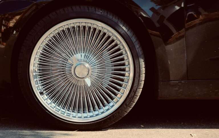 Detailed view of a classic spoked wheel rim on a black car, showcasing retro style.