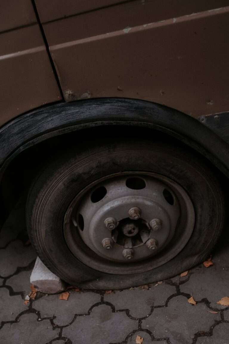 Detailed view of a flat tire on a car parked on a paved surface outdoors.
